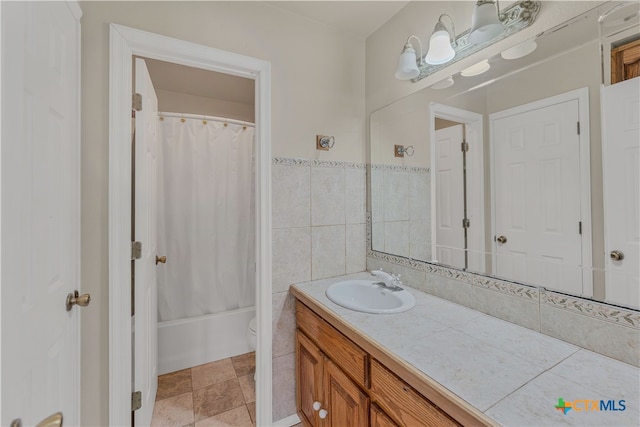 full bathroom featuring toilet, vanity, tile walls, and shower / bathtub combination with curtain