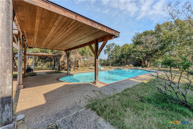 view of swimming pool featuring a water slide, a lawn, and a patio