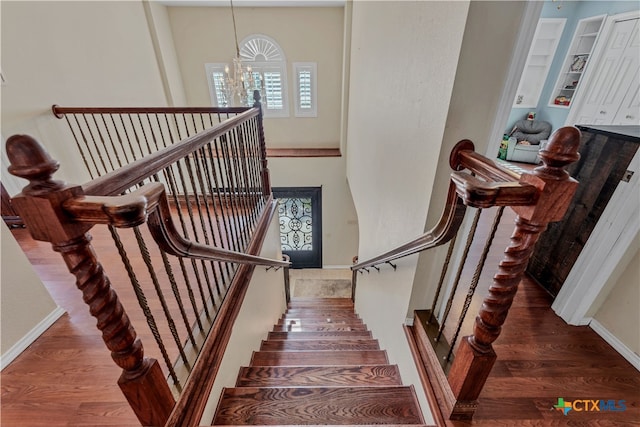 stairs featuring hardwood / wood-style flooring and a notable chandelier