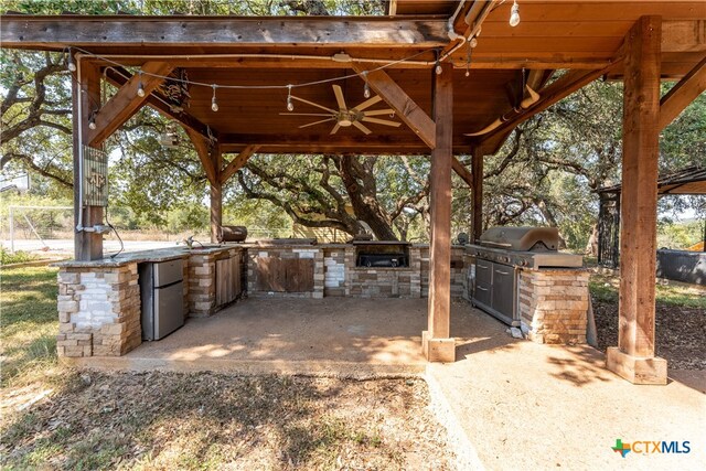 view of patio featuring ceiling fan, exterior kitchen, a gazebo, and grilling area