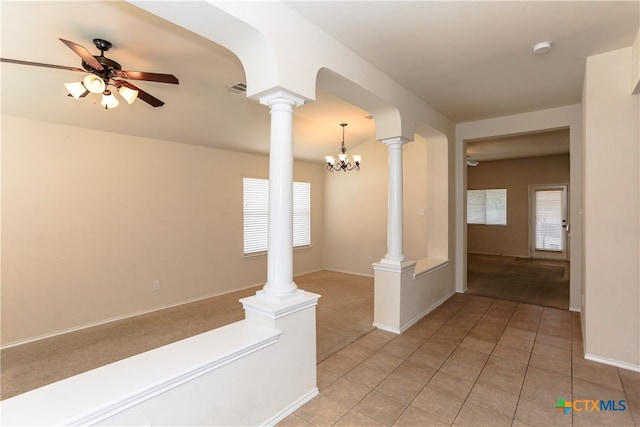 corridor with decorative columns, light colored carpet, a notable chandelier, and a healthy amount of sunlight