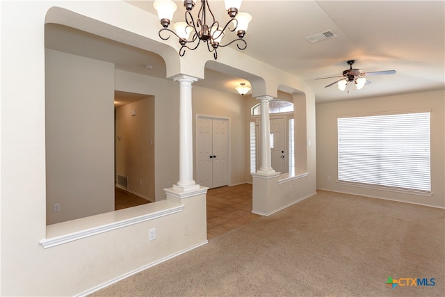 carpeted spare room with ceiling fan with notable chandelier and ornate columns