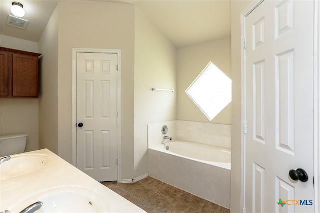 bathroom featuring toilet, vaulted ceiling, tile patterned flooring, vanity, and a bath