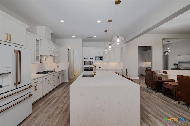 kitchen with white cabinets, pendant lighting, appliances with stainless steel finishes, and a kitchen island with sink