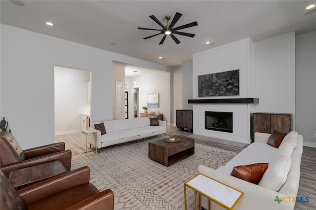 living room with a fireplace, light hardwood / wood-style floors, and ceiling fan