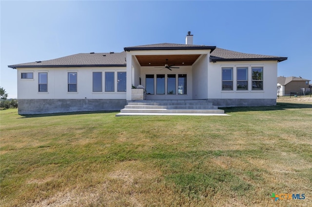 back of property with ceiling fan and a yard