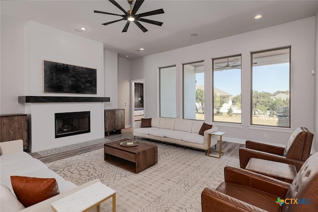 living room featuring a fireplace, wood-type flooring, and ceiling fan