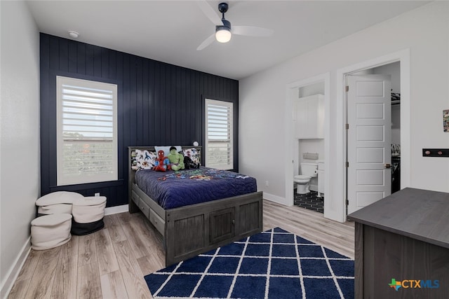 bedroom with ceiling fan, connected bathroom, wooden walls, and wood-type flooring