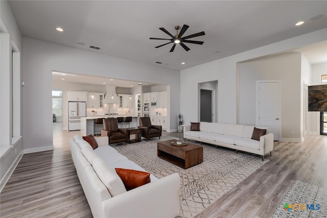 living room with ceiling fan and light hardwood / wood-style flooring