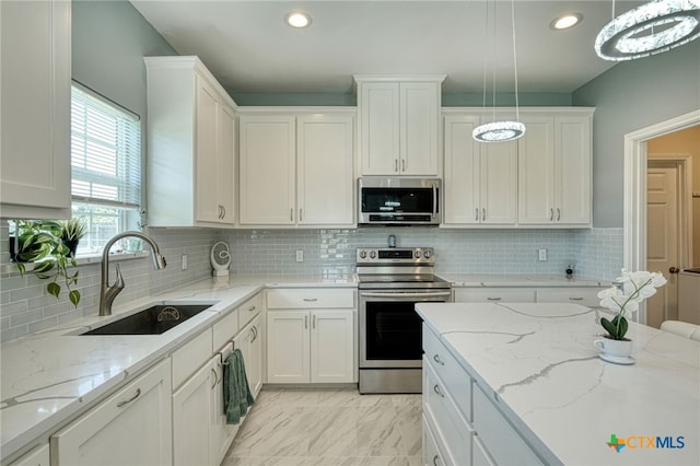 kitchen with pendant lighting, appliances with stainless steel finishes, white cabinetry, and sink