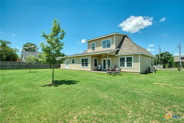 rear view of property with central AC unit, a patio area, and a yard