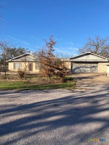 view of front of home with stucco siding, a detached garage, an outdoor structure, and driveway