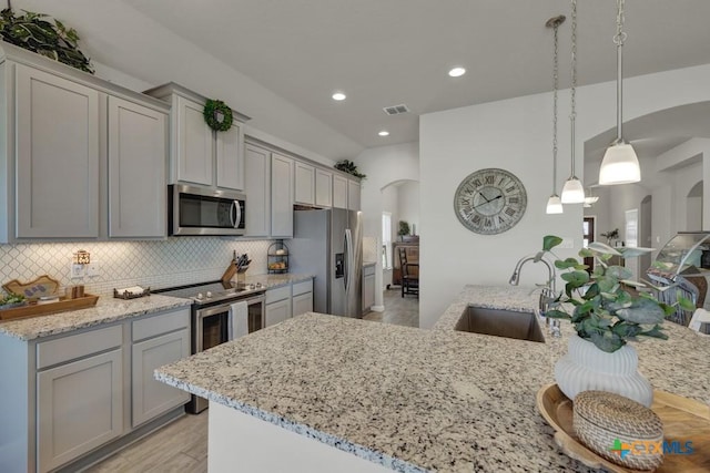 3214 Roan St, New Braunfels, TX 78130 - kitchen featuring stainless steel appliances, arched walkways, gray cabinets, decorative backsplash, and recessed lighting