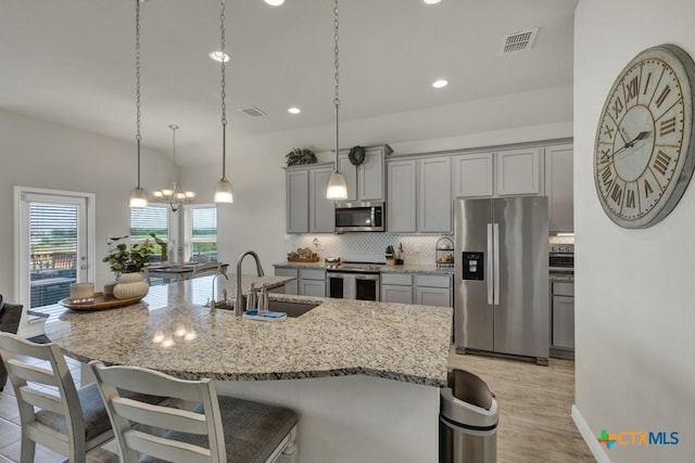 3214 Roan St, New Braunfels, TX 78130 - kitchen featuring appliances with stainless steel finishes, gray cabinets, a breakfast bar, tasteful backsplash, and recessed lighting
