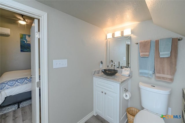 bathroom with toilet, an AC wall unit, lofted ceiling, wood finished floors, and vanity