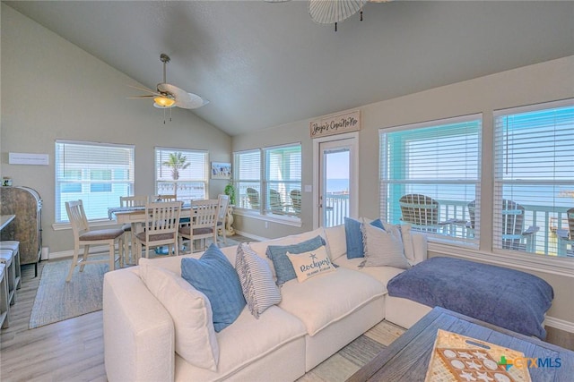 living room with baseboards, light wood-type flooring, ceiling fan, and vaulted ceiling