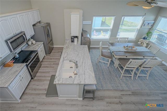 kitchen featuring light stone counters, appliances with stainless steel finishes, light wood-style flooring, and white cabinetry