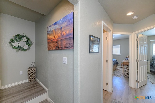 corridor with baseboards and light wood-style floors