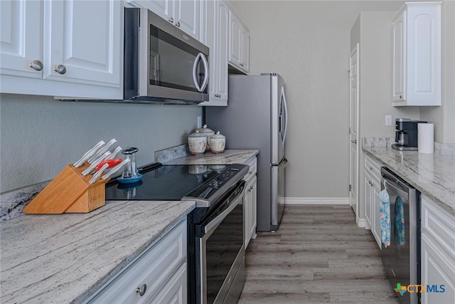 kitchen featuring light stone counters, stainless steel appliances, baseboards, and white cabinets