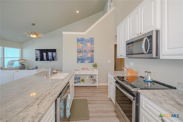 kitchen with light stone countertops, lofted ceiling, a sink, white cabinets, and appliances with stainless steel finishes