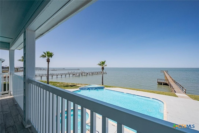 balcony featuring a water view and a pool with connected hot tub