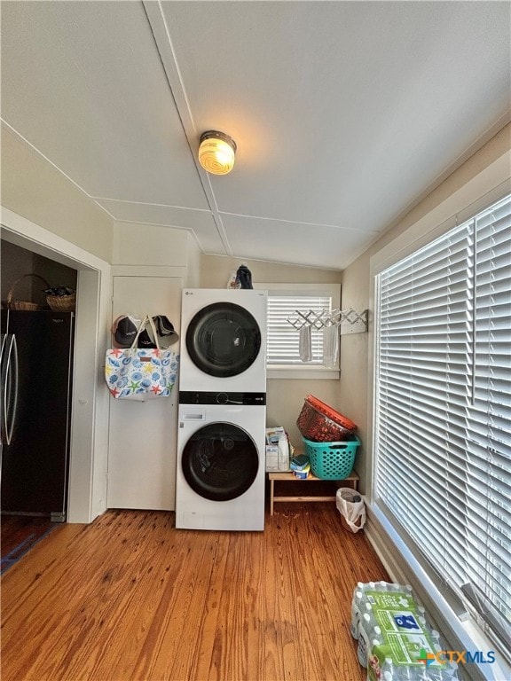 laundry area with stacked washing maching and dryer and light hardwood / wood-style flooring