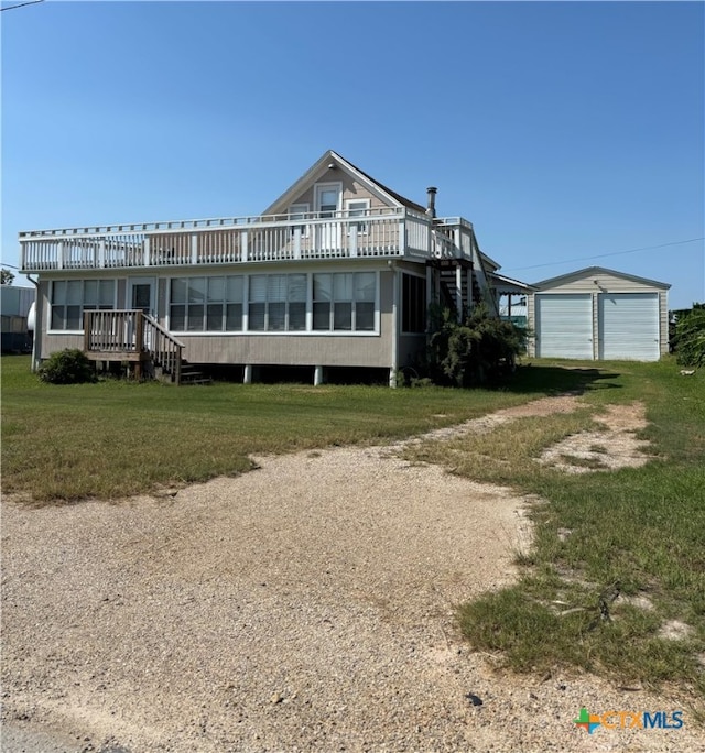 rear view of house featuring an outbuilding, a garage, a lawn, and a deck