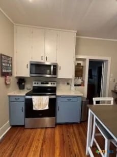 kitchen with dark hardwood / wood-style flooring, white cabinets, ornamental molding, and stainless steel appliances