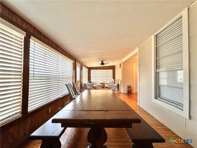 interior space with wood walls, ceiling fan, and light wood-type flooring