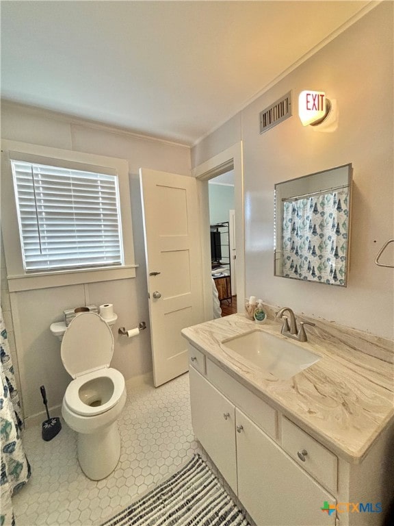 bathroom with toilet, vanity, and tile patterned floors