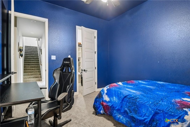 bedroom featuring a textured wall, carpet flooring, ceiling fan, and an office area