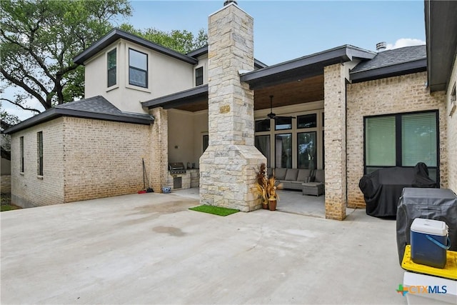 rear view of house featuring a patio area, a ceiling fan, a chimney, and brick siding