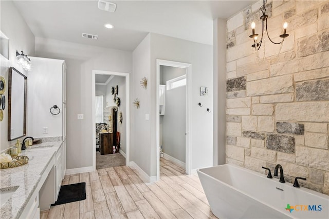 bathroom with a freestanding bath, double vanity, and wood finished floors