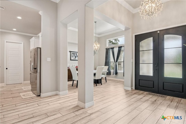 entrance foyer with a chandelier, ornamental molding, french doors, light wood-type flooring, and recessed lighting