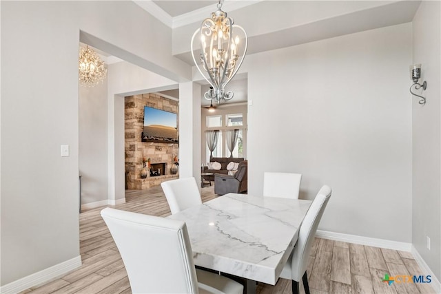 dining area with a chandelier, light wood-type flooring, and a fireplace with raised hearth