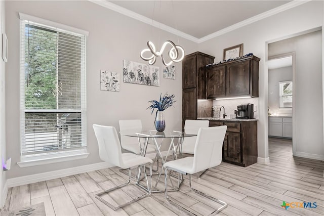 dining space with ornamental molding, a chandelier, and light wood-style flooring
