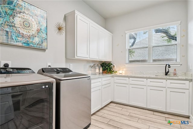 washroom featuring separate washer and dryer, light wood-style flooring, and cabinet space