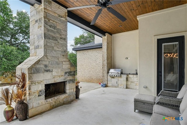 view of patio with an outdoor stone fireplace, area for grilling, and ceiling fan