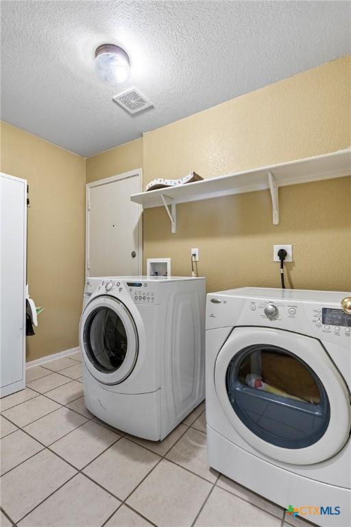 2604 Mikulec Dr, Killeen, TX 76542 - laundry area with washing machine and dryer, a textured ceiling, and light tile patterned floors