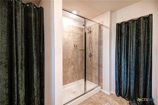 bathroom with a tile shower, a textured ceiling, and tile patterned floors