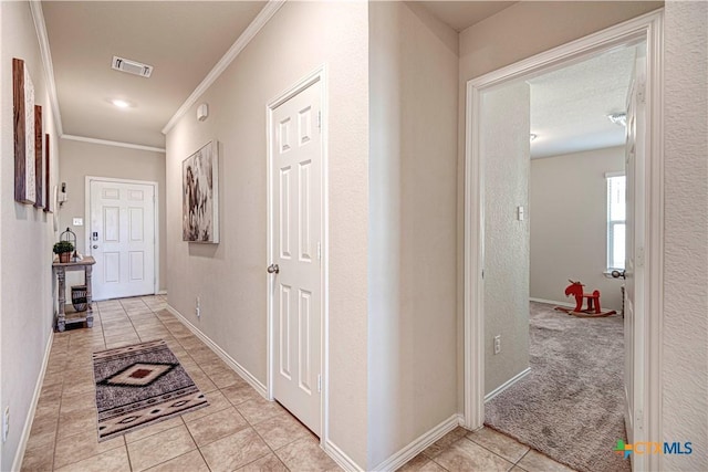 hallway with light tile patterned flooring and crown molding