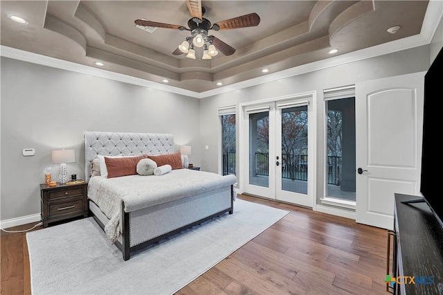 bedroom featuring ceiling fan, access to exterior, french doors, dark hardwood / wood-style flooring, and a raised ceiling