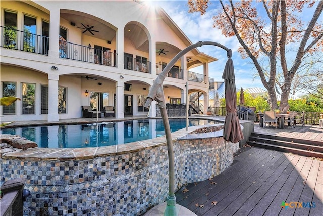 view of swimming pool with a wooden deck and ceiling fan