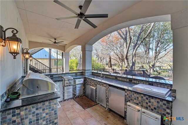 view of patio / terrace featuring ceiling fan, an outdoor kitchen, a grill, and sink