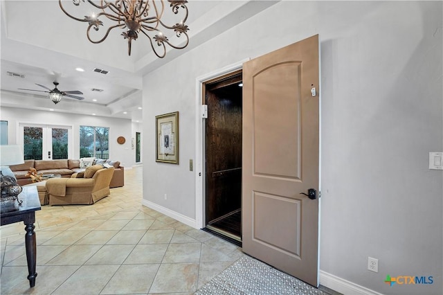 corridor featuring an inviting chandelier, a tray ceiling, and light tile patterned floors