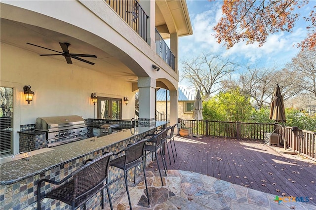 wooden deck featuring area for grilling, a bar, and ceiling fan