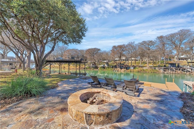 view of patio featuring a water view, a fire pit, and a boat dock