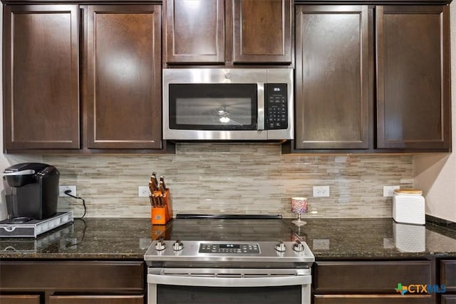 kitchen with appliances with stainless steel finishes, dark brown cabinets, and dark stone counters