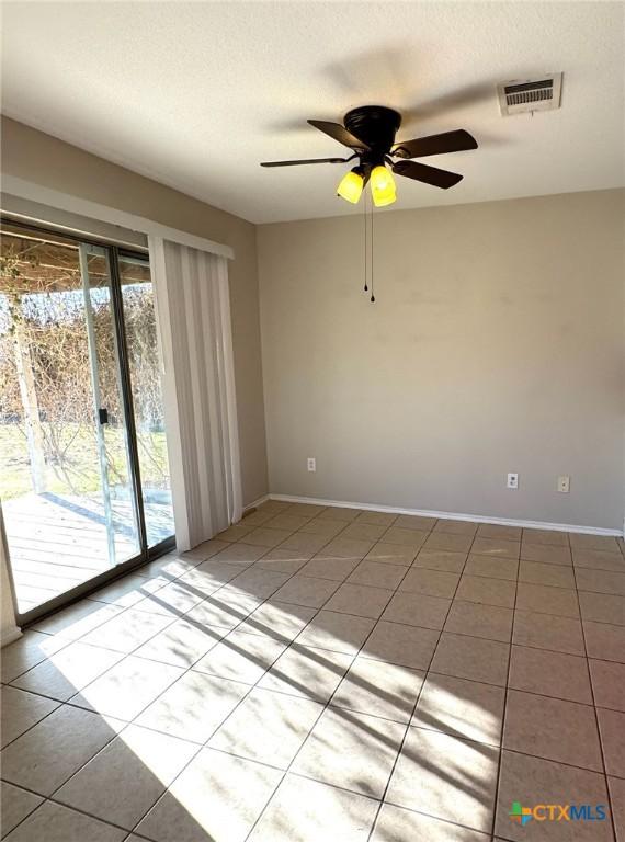 tiled empty room featuring ceiling fan and a textured ceiling