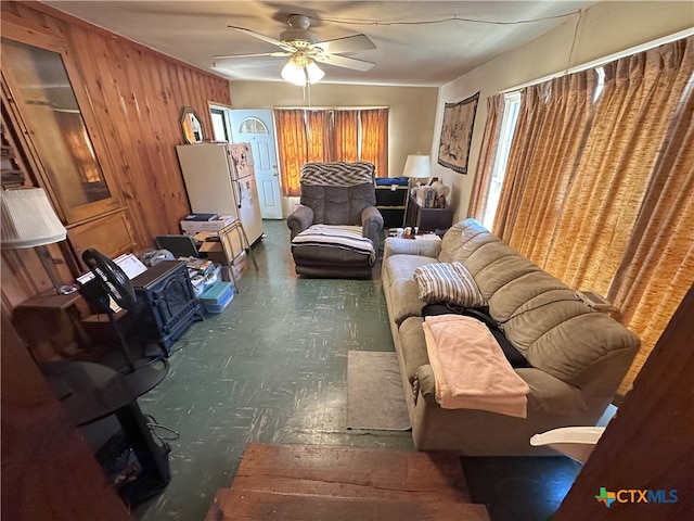 living room with ceiling fan and wooden walls